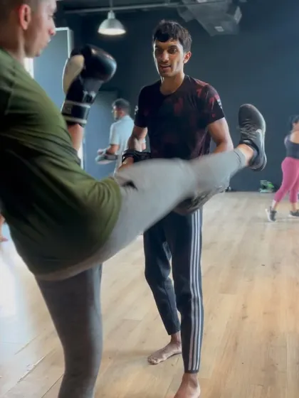 Another shot of a member practicing their kicks with a coach's guidance.