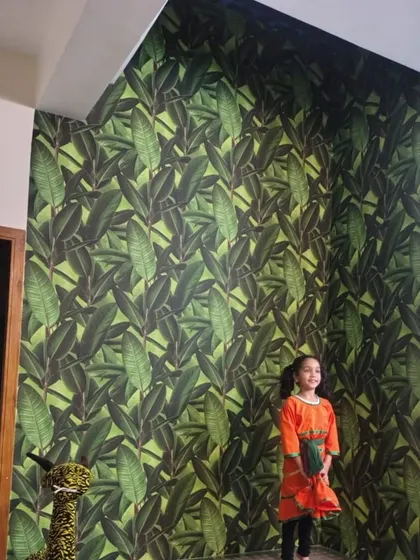 A vibrant green leaf wallpaper makes a fun and lively accent wall. The large-scale pattern brings a burst of nature indoors and creates a playful backdrop.