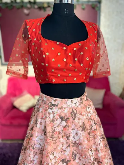 A closer look at the red blouse, showing the sweetheart neckline and delicate gold motifs.