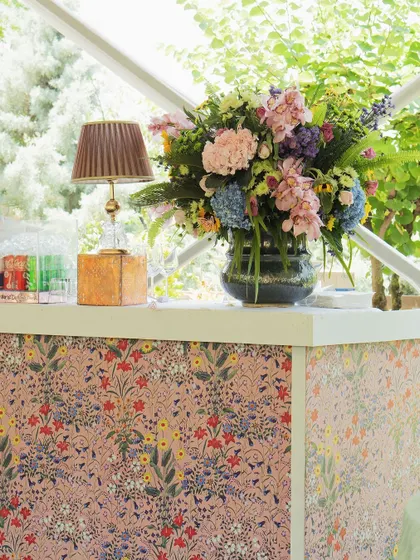 The bar was wrapped in a delicate floral print, topped with a large, vibrant bouquet, blending seamlessly with the garden surroundings.