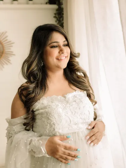 A solo portrait of the glowing mom-to-be. The off-the-shoulder white lace gown adds a touch of elegance and romance to this beautiful maternity photo.