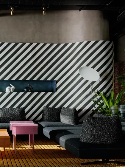 A closer view of the graphic striped wall and modular sofa. The built-in shelf adds a block of color, while the oversized floor lamp provides sculptural lighting.