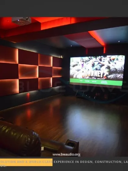 This casual theater setup uses comfortable leather sofas and a large, open floor space. The back-lit acoustic wall panels provide both a stylish design element and essential sound absorption for clear audio.
