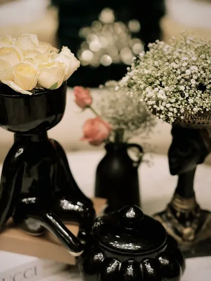 Unique black ceramic vases with white roses, used as chic and modern centerpieces for a cocktail party.