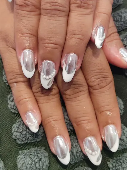 A bold and unique design combining a white base with a high-shine silver chrome effect and delicate pearl accents on almond-shaped nails.