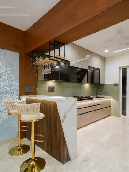 This luxurious kitchen design includes a stylish breakfast bar with gold-accented stools. The mix of materials, including marble, wood, and textured panels, creates a very high-end look.