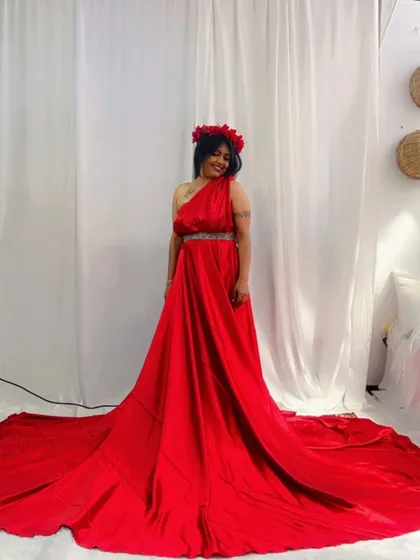 A beautiful red satin gown with a long trail, styled with a floral crown for a goddess-inspired look.