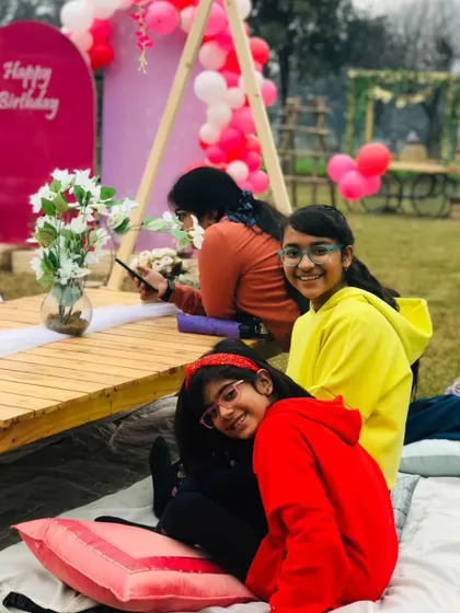 A group of smiling girls posing for a photo at their friend's outdoor birthday party.