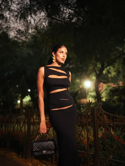 A full-length shot showcasing the entire Christopher Esber dress and Chanel bag. The composition and lighting are designed to create a sophisticated and aspirational lifestyle image.