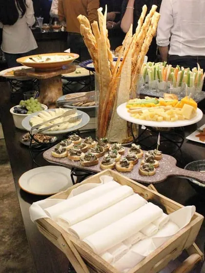 A view of guests enjoying our buffet at an exclusive home gathering. The setup includes tall grissini, cheese platters, and various canapés, designed to facilitate conversation and mingling.