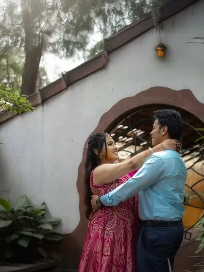 A happy, candid embrace in a beautiful garden setting with distinct architecture. This shot captures the joy and ease of the couple's relationship.