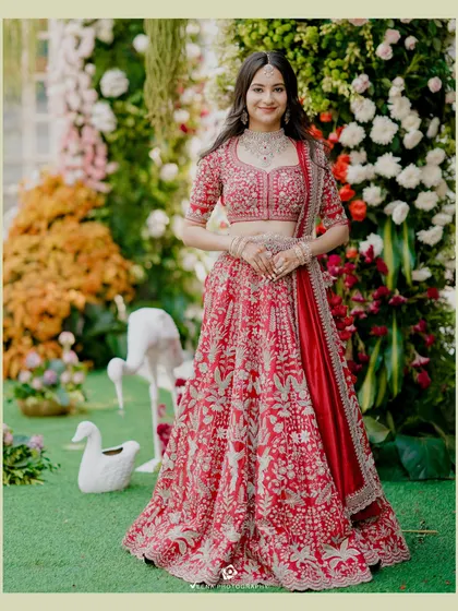 The bride looking radiant against the backdrop of a lush floral wall. The mix of colorful flowers and greenery provided a beautiful setting for her engagement photos.
