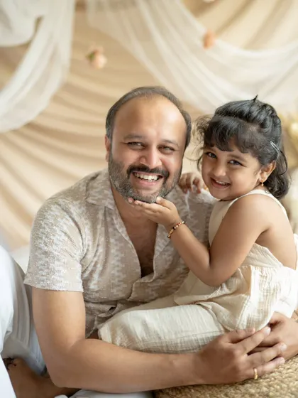 A daughter playfully touches her father's face, and they both share a big smile. A wonderful, interactive moment between a dad and his little girl.