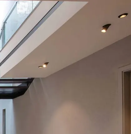 A detail of minimalist ceiling spotlights and the clean junction between the wall and a floating balcony edge.