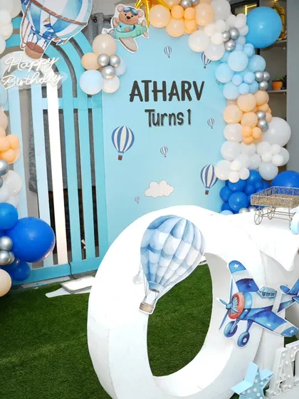 Atharv's first birthday was an "Up, Up, and Away" adventure. This hot air balloon and airplane theme features a large "ONE" table, a sky-blue backdrop, and fluffy balloon clouds.