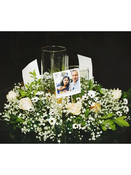 A personal touch for a table centerpiece. We incorporated a small photo of the couple into this delicate arrangement of baby's breath and white roses.