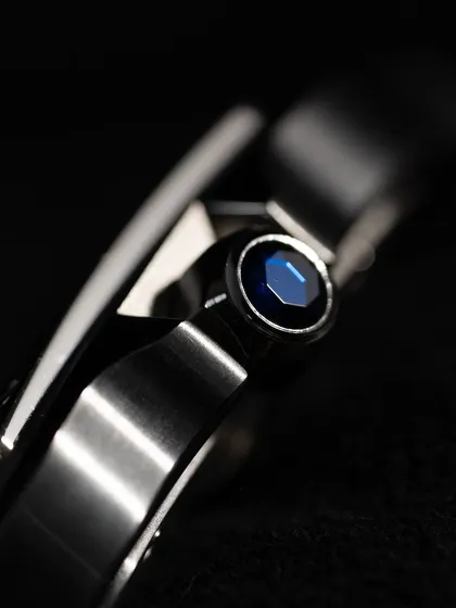 A macro detail of the faceted blue synthetic spinel set into the crown. This is a signature Cartier detail that adds a subtle touch of color and luxury.