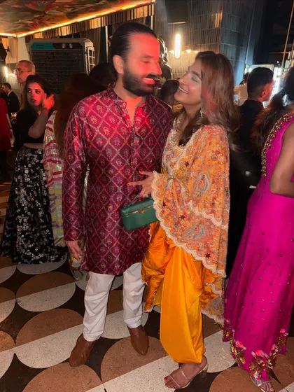 A candid moment with my husband. His classic maroon kurta and my yellow Anamika Khanna outfit show how couples can coordinate with complementary colors.