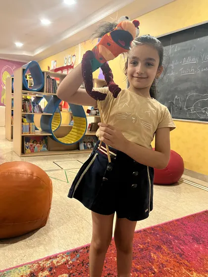 This student is thrilled with her finished puppet. From design to creation, the entire process builds fine motor skills and a sense of accomplishment.