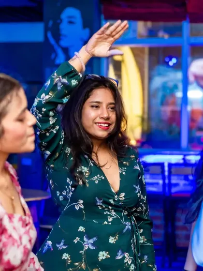 A guest with her hand up, dancing to the beat. The floral dress and happy expression capture the fun, carefree vibe.