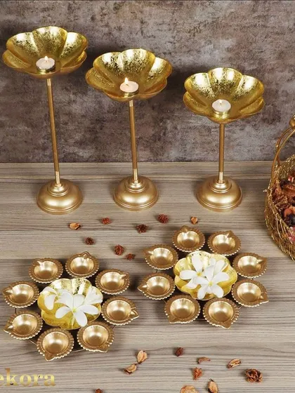 This image showcases a variety of our festive lighting options, including tall lotus candle stands and multi-diya plates. These items can be ordered in bulk to create a cohesive decorative theme for corporate events.