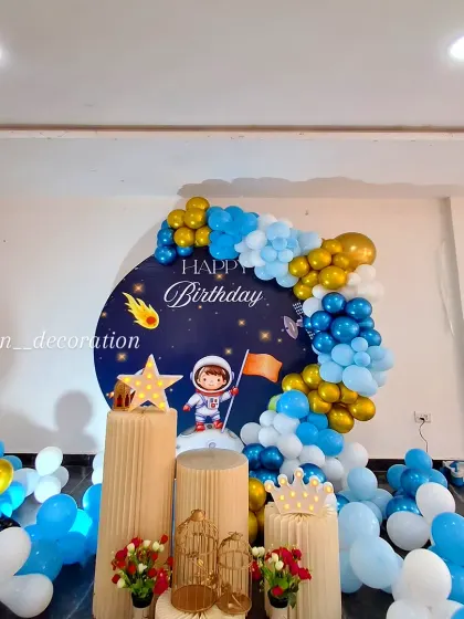 A space-themed birthday setup with a focus on the cake stands, featuring props like a star, a crown, and a decorative birdcage.