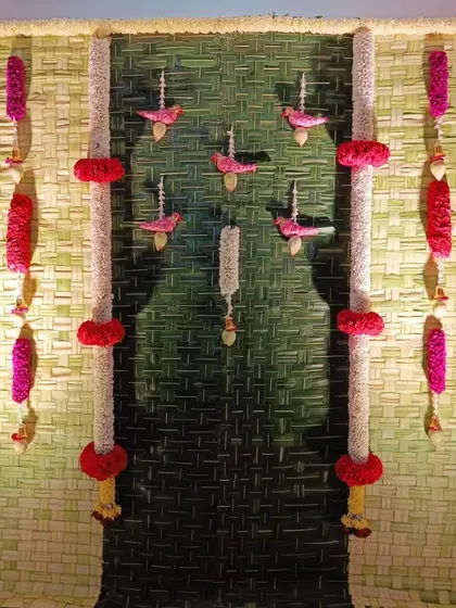 Another example of our detailed floral work for a Varamahalakshmi pooja. The backdrop features pillars of jasmine and red flowers, with delicate bird-shaped hangings that add a unique, handcrafted feel.