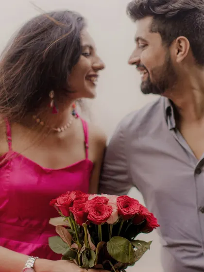 A classic romantic portrait with a bouquet of red roses, capturing the genuine smiles that blossom during an arranged marriage story.