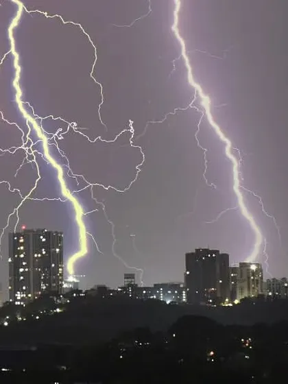 Another perspective of the urban thunderstorm, showing the contrast between the dark silhouettes of the buildings and the bright, chaotic energy of the lightning.