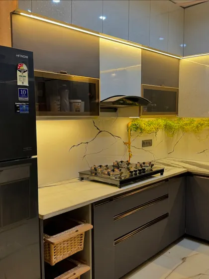This L-shaped kitchen showcases a beautiful combination of grey and white laminates, with a stunning marble-patterned backsplash that has integrated lighting.