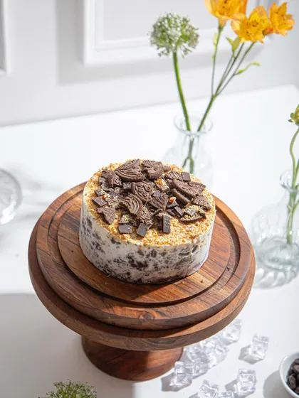 A close-up of the Cookies and Cream ice cream cake, focusing on the generous topping of crushed chocolate cookies.