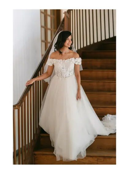 A bride in her flowing white gown, smiling as she descends a wooden staircase. This shot is full of movement and captures her joyful anticipation.