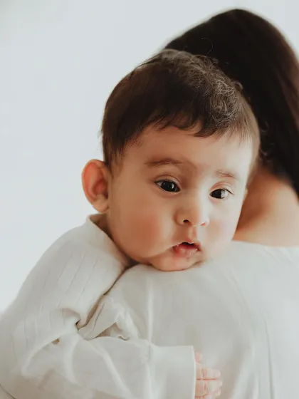 A close-up of a baby peeking over its mother's shoulder. This angle provides a unique and intimate perspective on their bond.