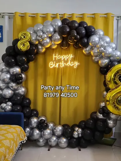 A black and silver circular balloon arch set up in a living room for an 8th birthday party.