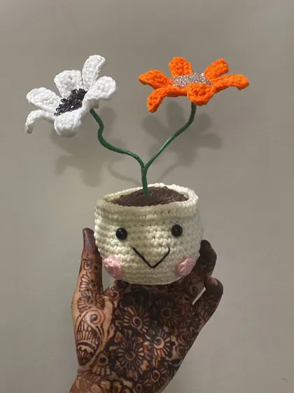 My hand, covered in mehndi, holding the custom beaded daisy pot. It’s a beautiful reminder of the blend of tradition and modern craft in my work.
