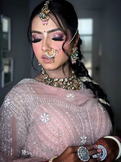 A soft and ethereal bridal look. The pink glittery eyes, braided hair, and delicate jewelry create a dreamy and modern bridal style.