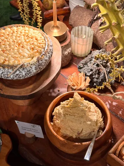 A close-up of our rustic grazing table, featuring a wheel of cheese and a bowl of creamy hummus.