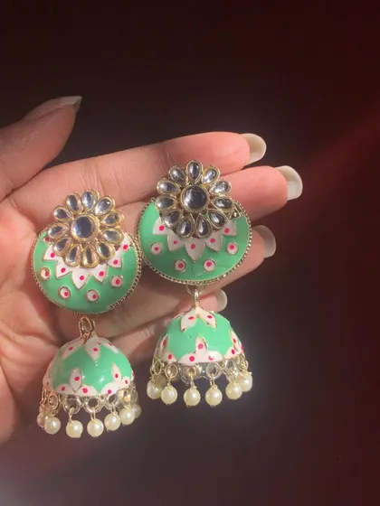 A sold-out favourite, these pastel green Meenakari jhumkas are adorned with a kundan flower and delicate pearl drops. This design is always highly requested.