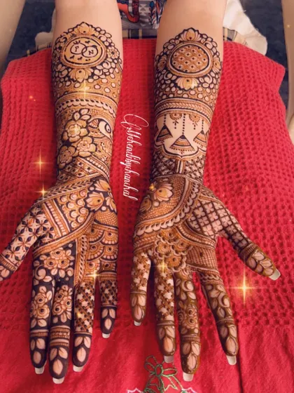A grand engagement mehendi featuring the couple's initials, hanging 'jhumkas', and a mix of floral and geometric patterns.