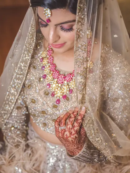 A beautiful bridal portrait focusing on the details. The bride's feathered lehenga, intricate henna, and stunning necklace are all captured in this elegant, downward-looking pose.