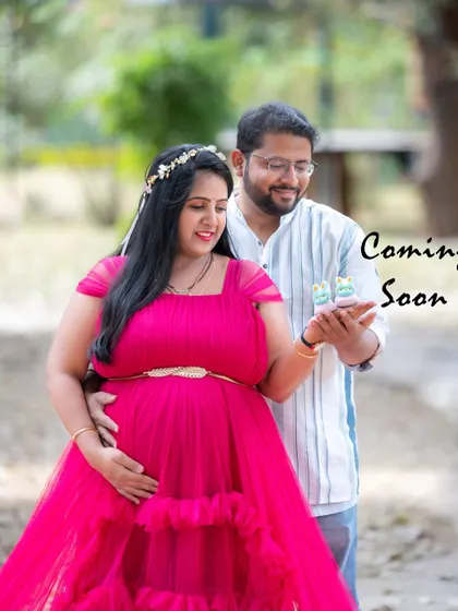 A sweet couple's photo with a "Coming Soon" message, featuring tiny baby shoes.