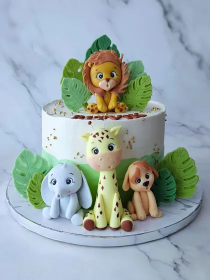 A butterscotch cake with Ritvik's favorite animals. This jungle-themed cake features a cute lion, elephant, giraffe, and dog, all handcrafted from fondant.
