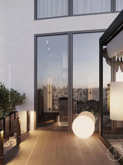 We create layered lighting schemes for outdoor spaces like this balcony. Here, a combination of glowing spherical floor lamps and low-level pathway bollards provides both ambient and functional light, turning the area into a cozy outdoor room.