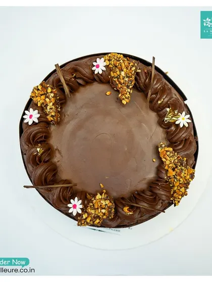 An overhead shot of the Chocolate Almond Nougatine cake, showing the balanced distribution of crunchy nougatine clusters and delicate sugar flowers.