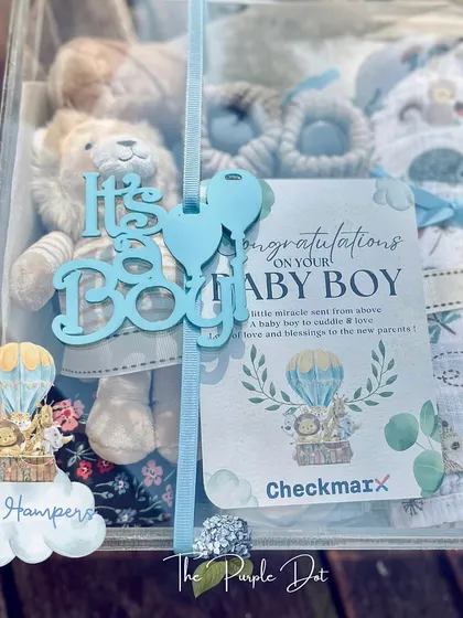 An acrylic box offers a modern way to present a baby gift. This one for a baby boy includes a plush lion, soft booties, and a custom congratulations card, all visible through the clear case.