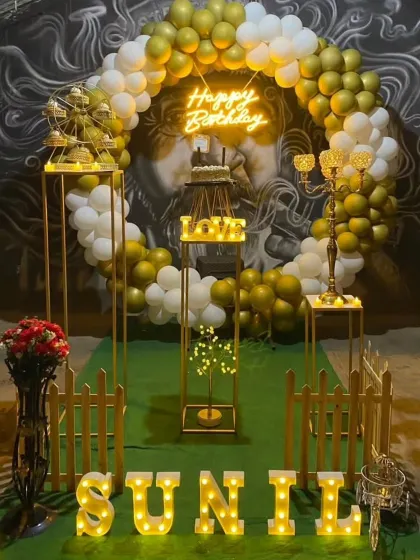 A grand birthday setup with a gold and white balloon arch against a mural backdrop, showcasing our ability to work with unique venue features.