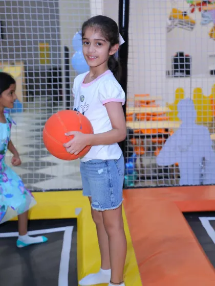 A young guest gets ready to play a game of dodgeball or basketball in our versatile trampoline court area.