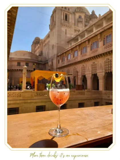 A beautiful pink mocktail with a passion fruit garnish, served against the stunning backdrop of a palace wedding.