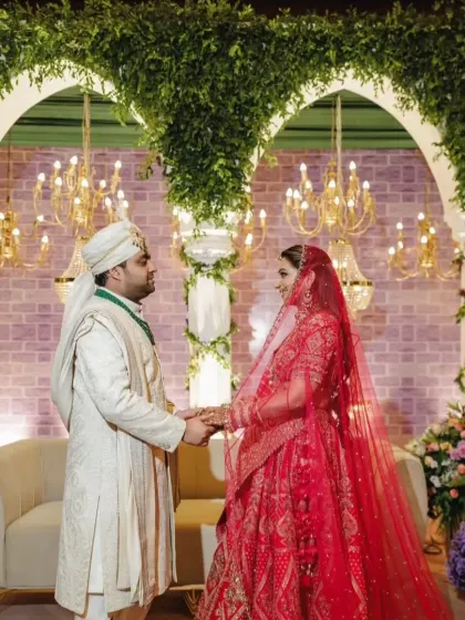 The couple, Arushi and Anirudh, share a moment during their Greek themed wedding ceremony. The backdrop features classic arches draped in greenery, creating a timeless and romantic setting for their vows.