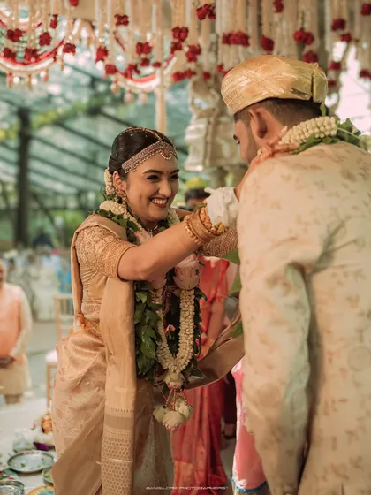 A happy moment of the garland exchange. The bride's joyful smile as she places the garland on her groom is a picture of pure happiness.